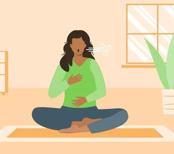 Kvinna sitter i skräddarställning och andas lugnt på en yogamatta