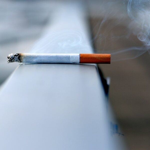 Tänd cigarett med glödande aska och virvlande rök
