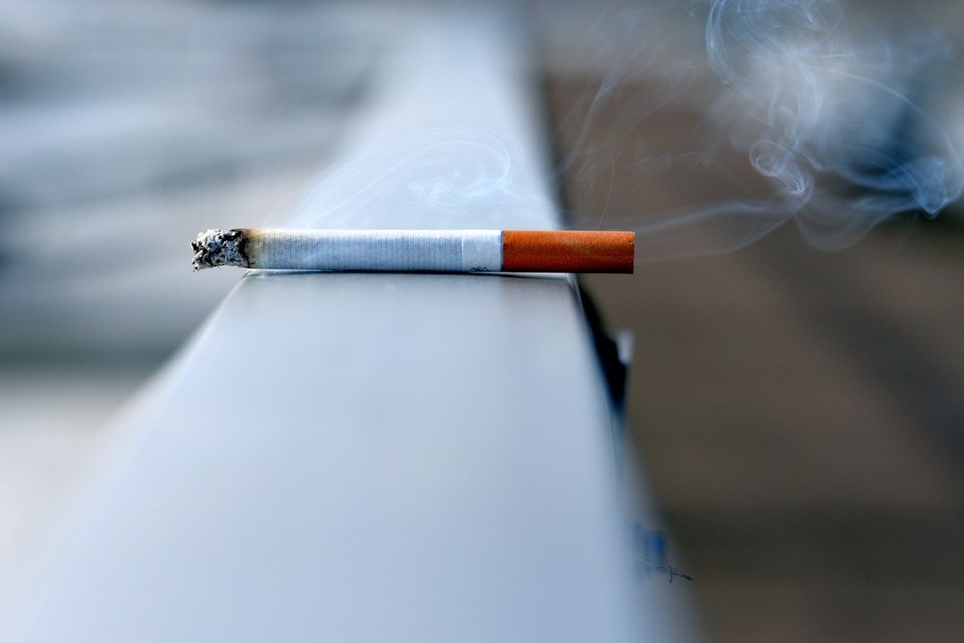 Tänd cigarett med glödande aska och virvlande rök